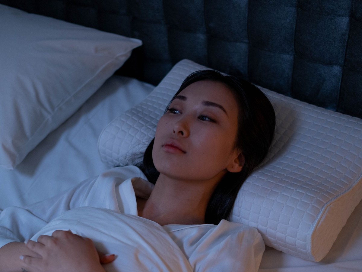 Donna sveglia di notte a letto, pensierosa nel buio